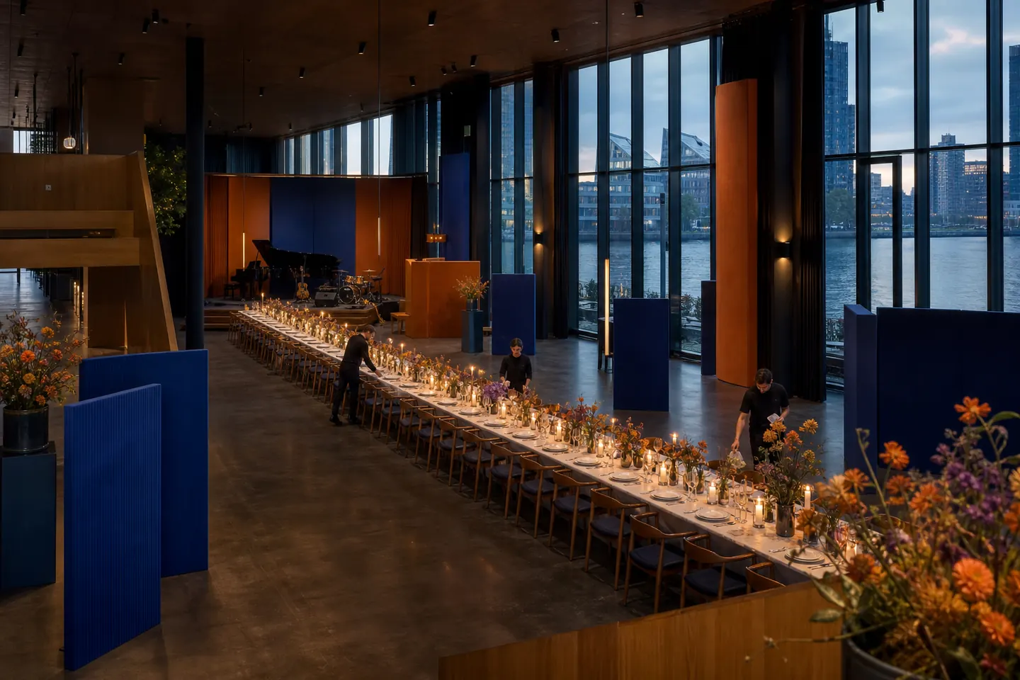 Evenementsalon met een lange gedekte tafel, podium en ramen aan de Maas